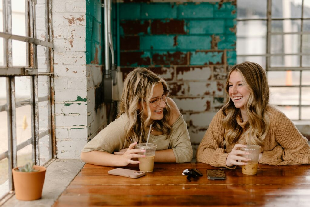 Two women talking and smiling over drinks, an open conversation about getting support